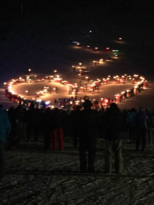 Torch-lit skiers form a heart to commemorate a fallen ski instructor